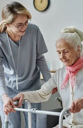 young-caregiver-caring-about-senior-woman-nursing-home-she-helping-her-stand-using-walker 1
